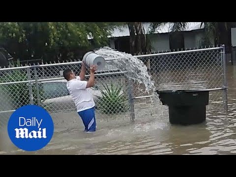 A man tries to drain a flood by using a bucket